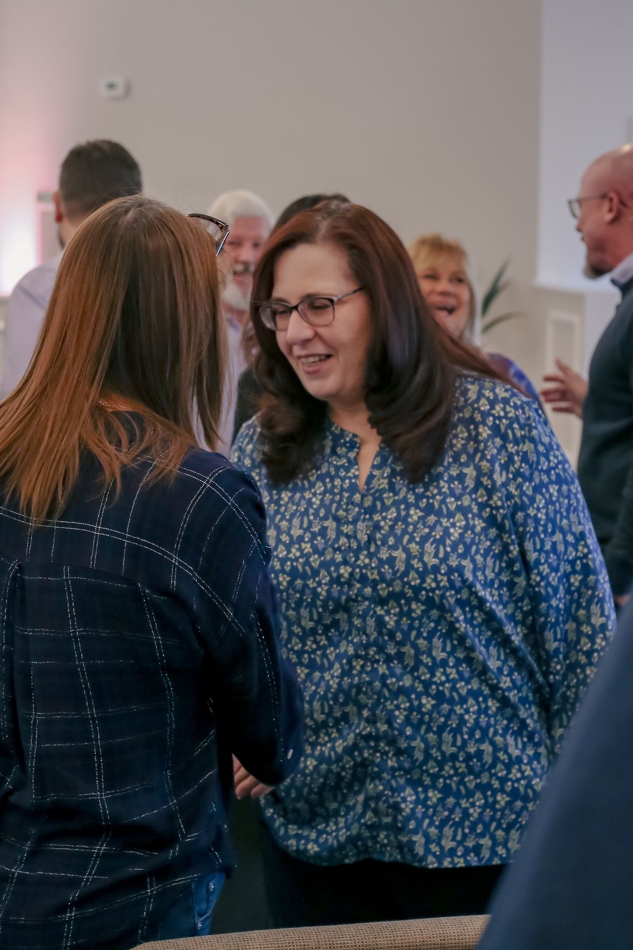 A group of people are standing around talking to each other in a room.