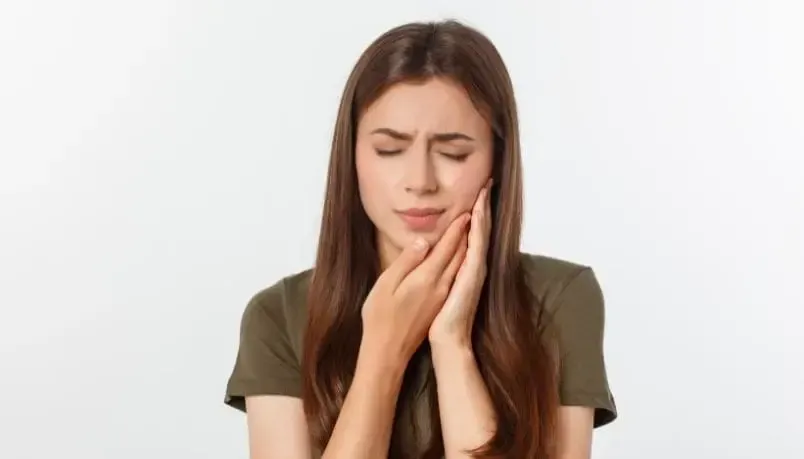 A woman is holding her face in pain because of a toothache.
