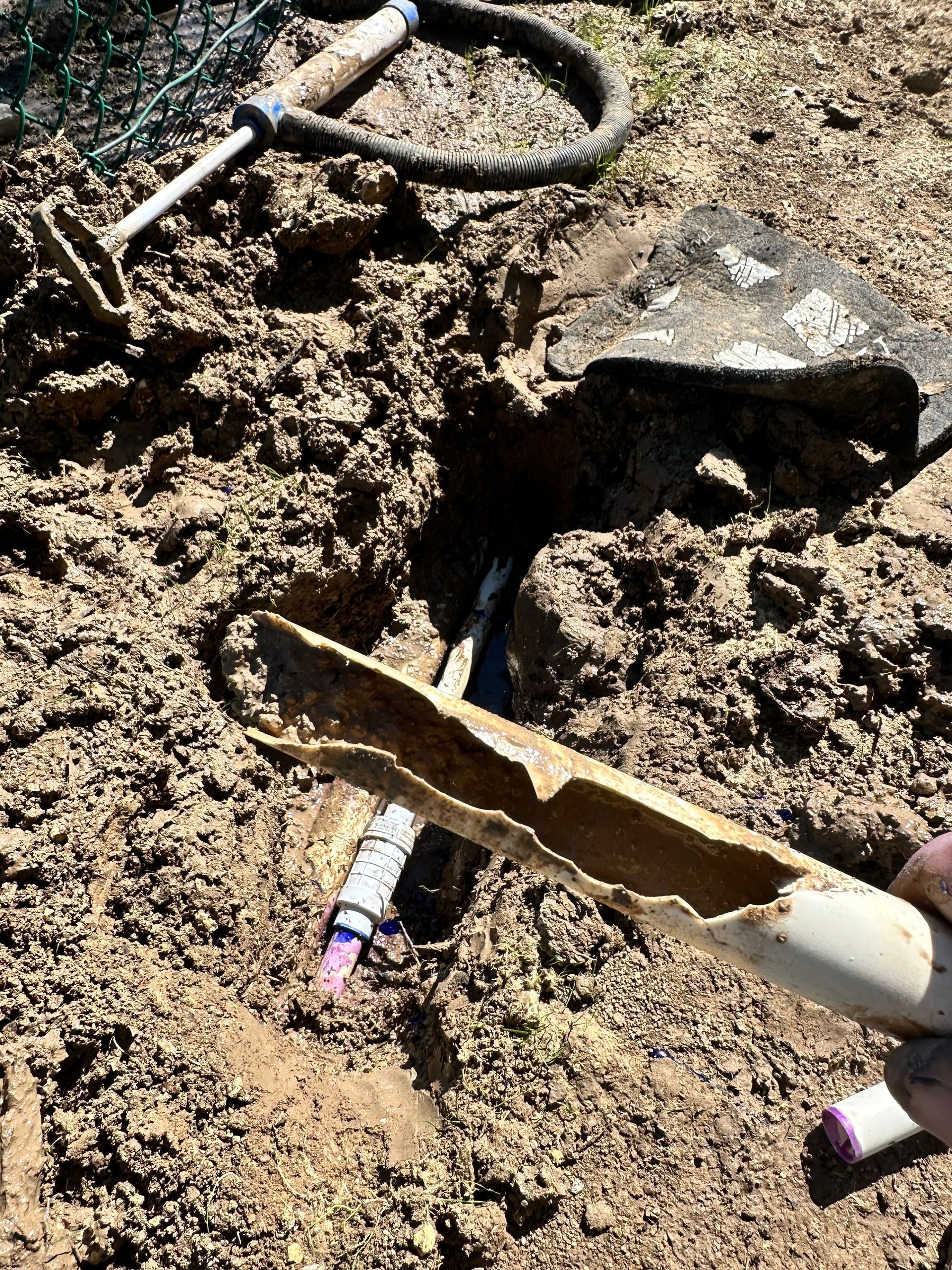 A person is digging in the dirt with a shovel and a marker.