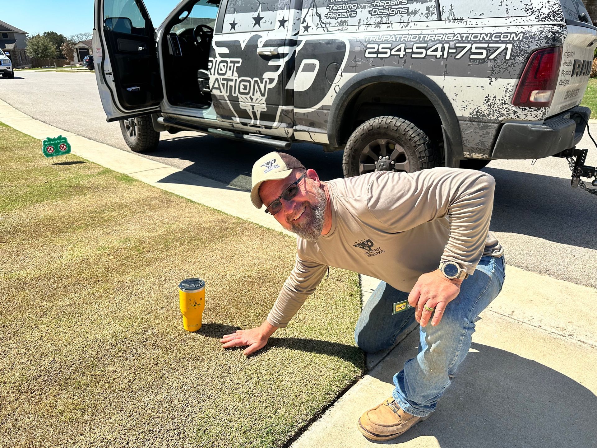A man is kneeling on the sidewalk next to a truck.