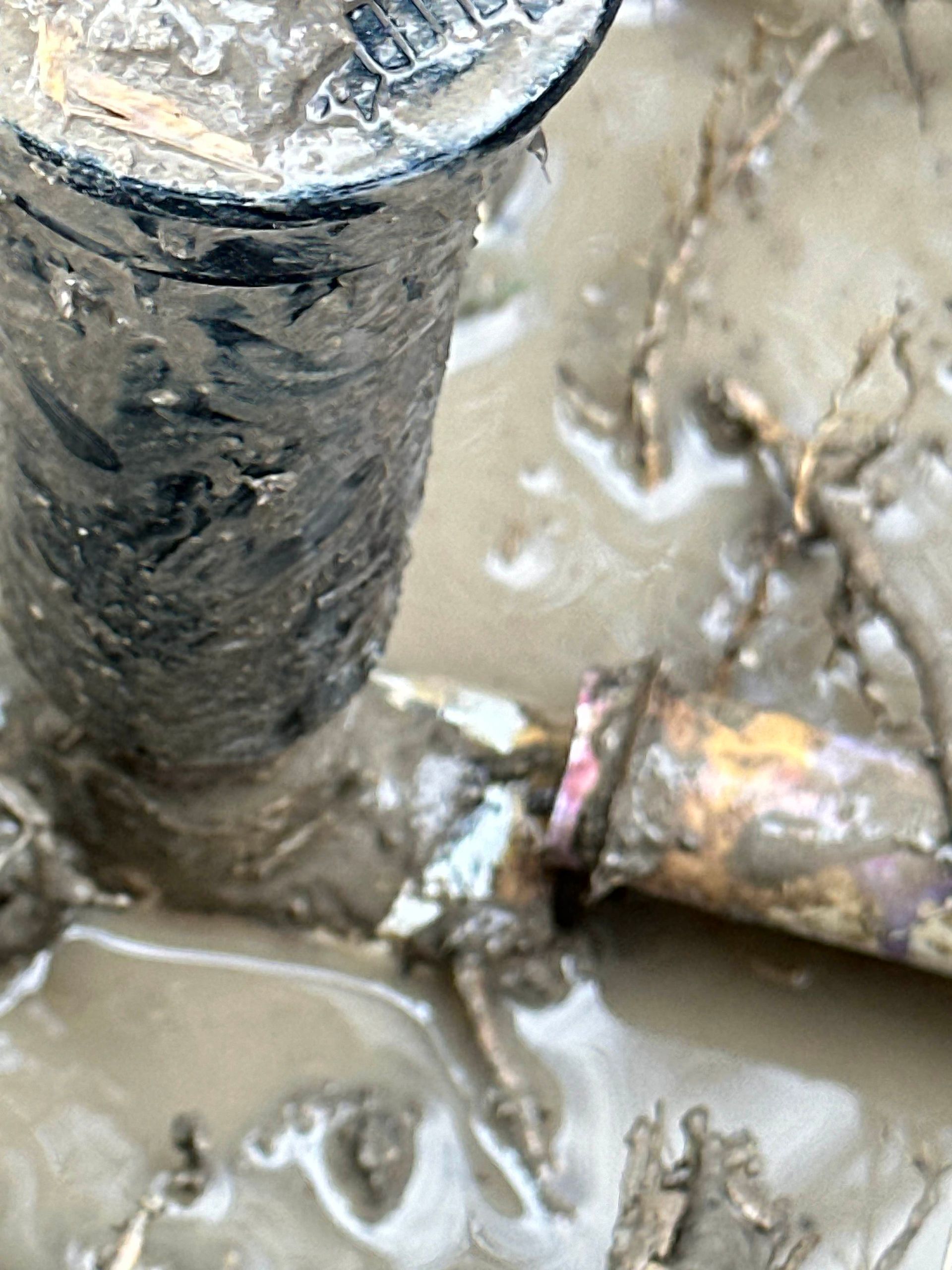 A close up of a screw in the mud.