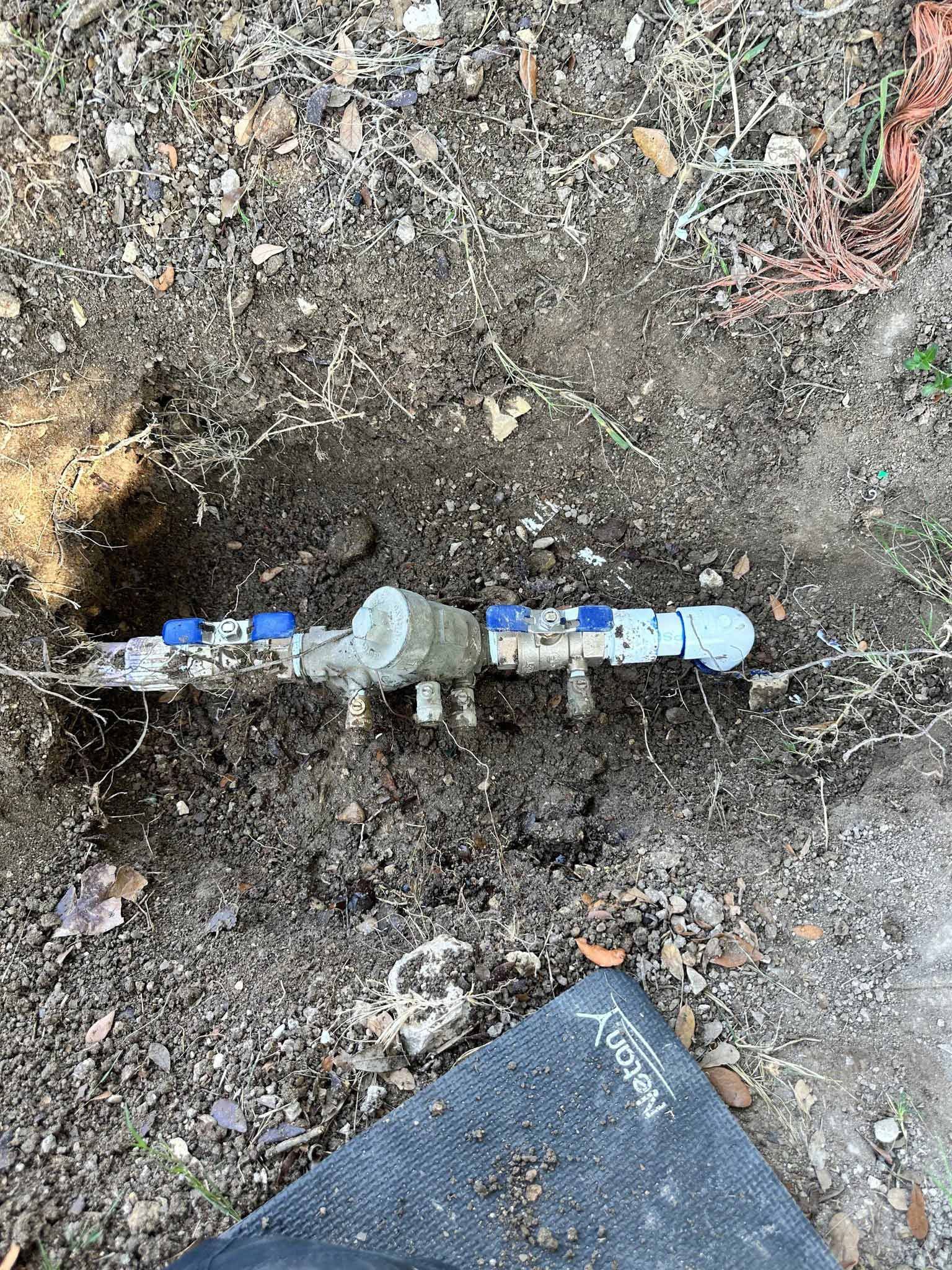 A water meter is sitting in the dirt on the ground.