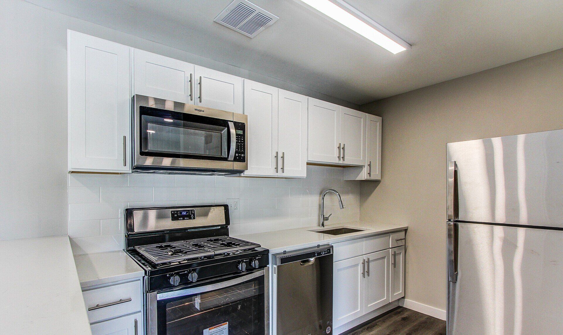 Modern white kitchen with stainless steel appliances and bright lighting