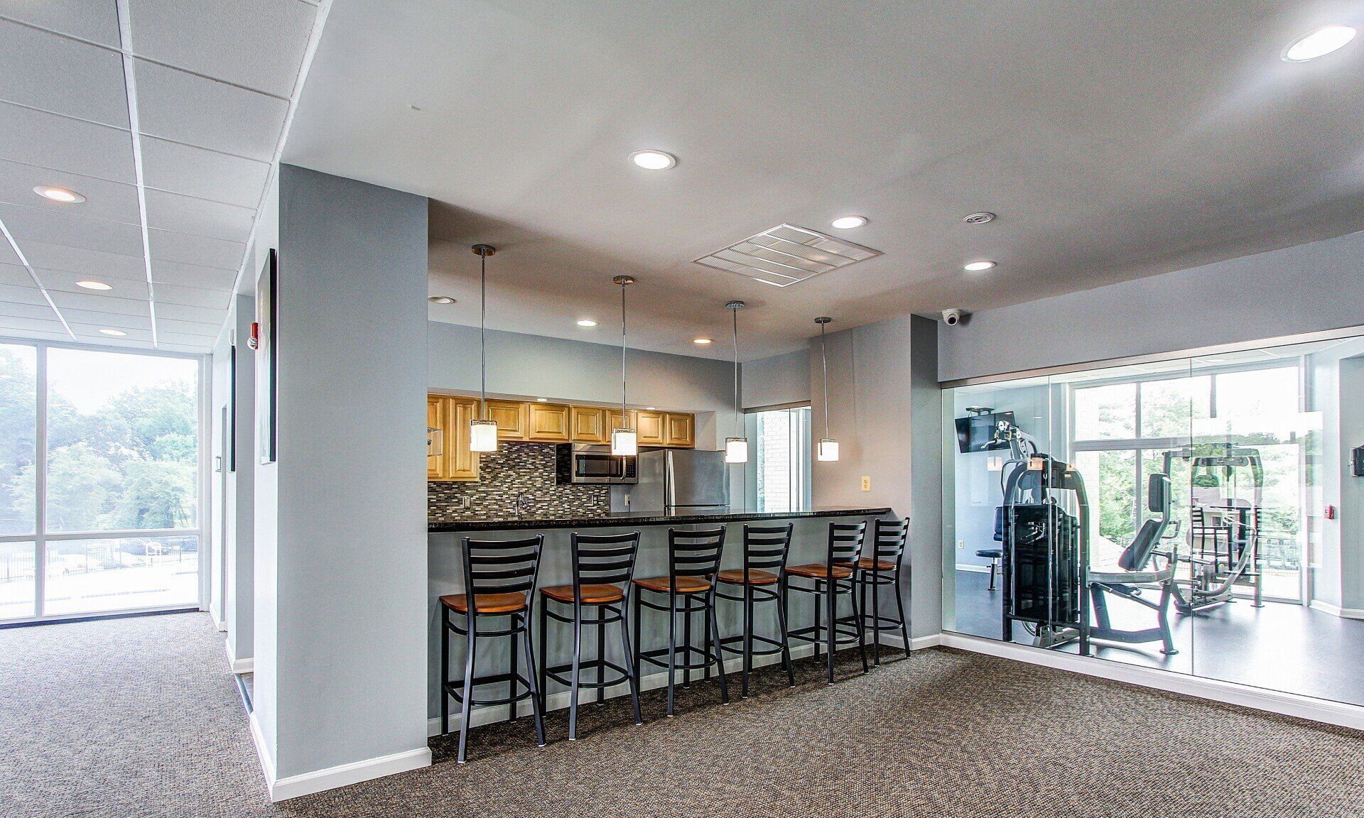 Modern gym lounge with bar seating, cable machine, and large windows