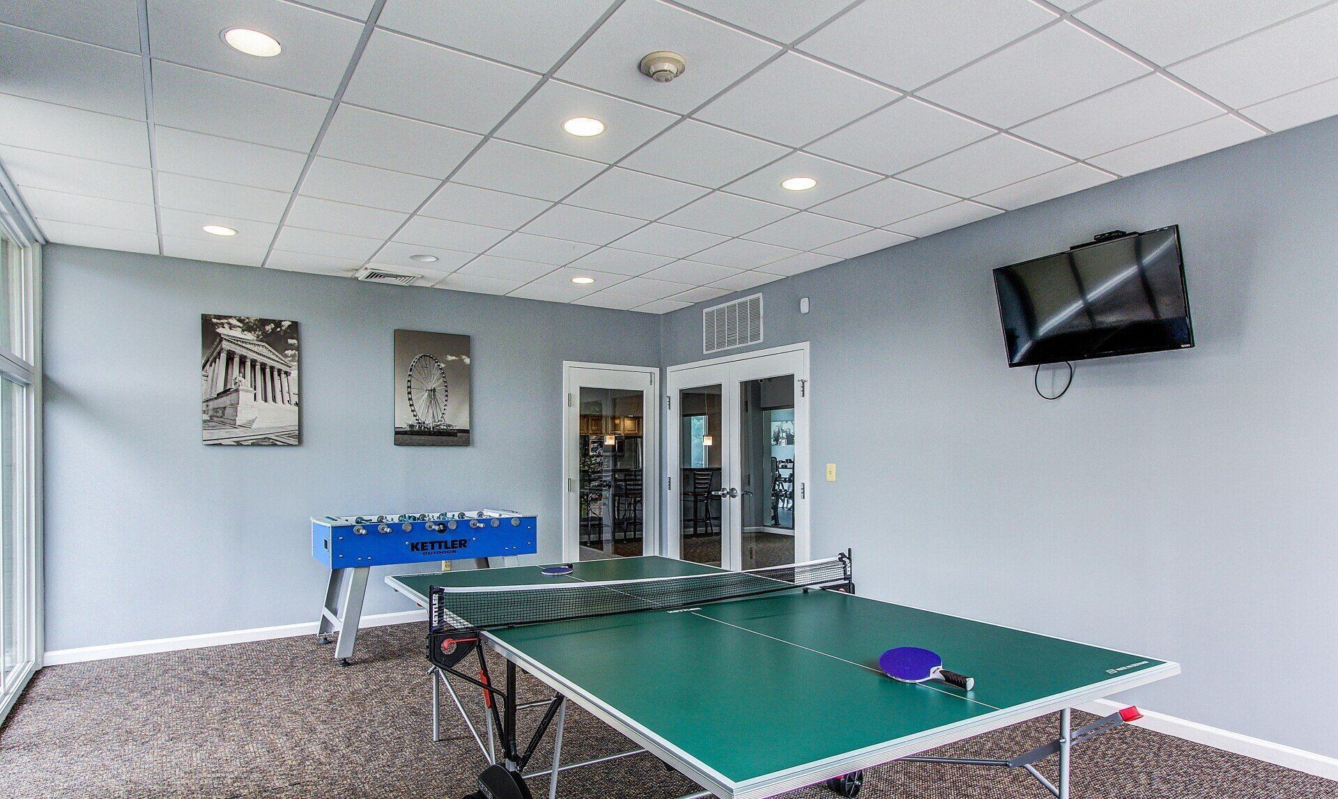 Recreation room with ping-pong table, foosball, wall-mounted TV, and blue tablecloth-covered table