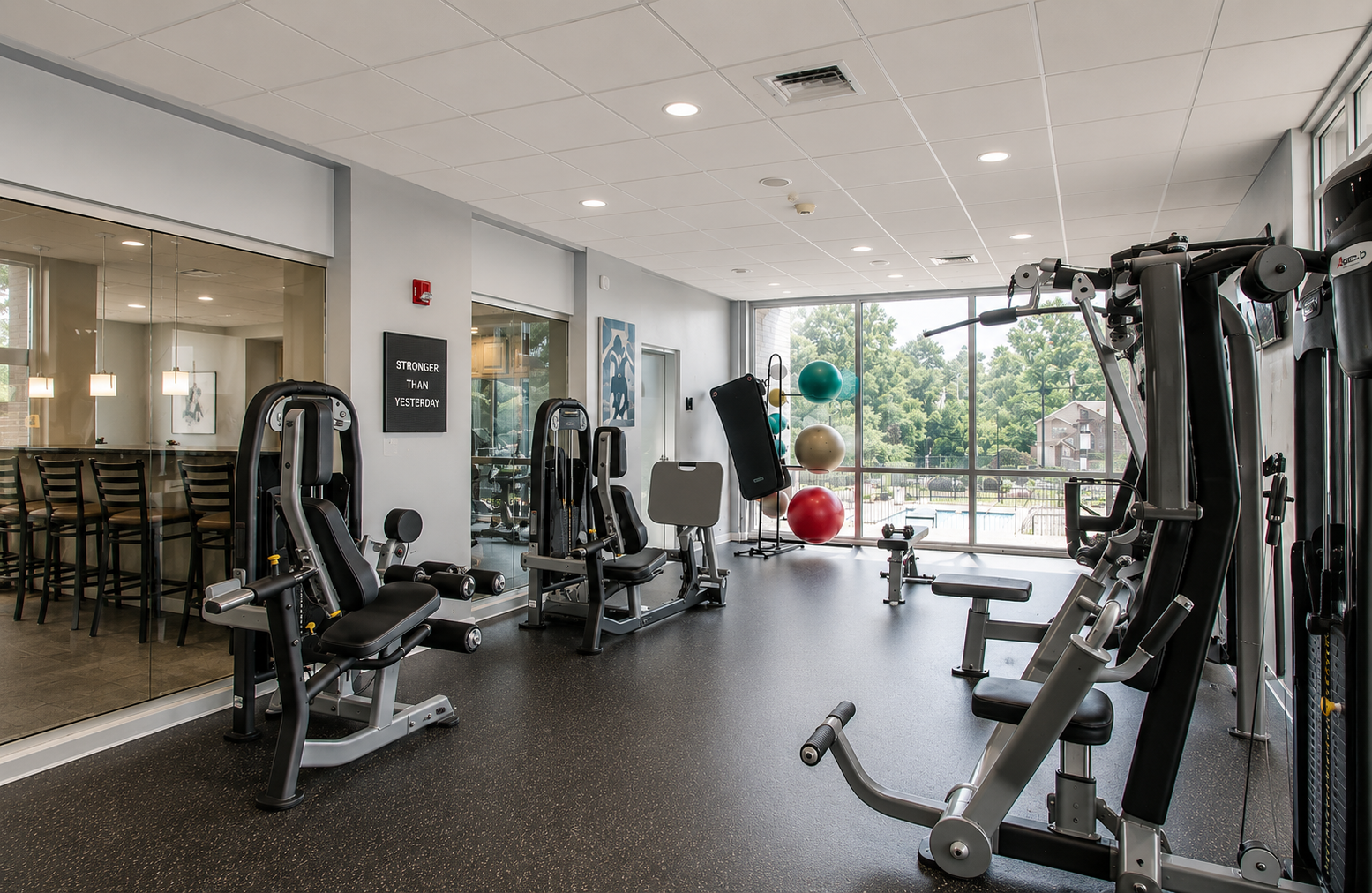 Bright gym with exercise machines, mirrors, and colorful stability balls near large windows