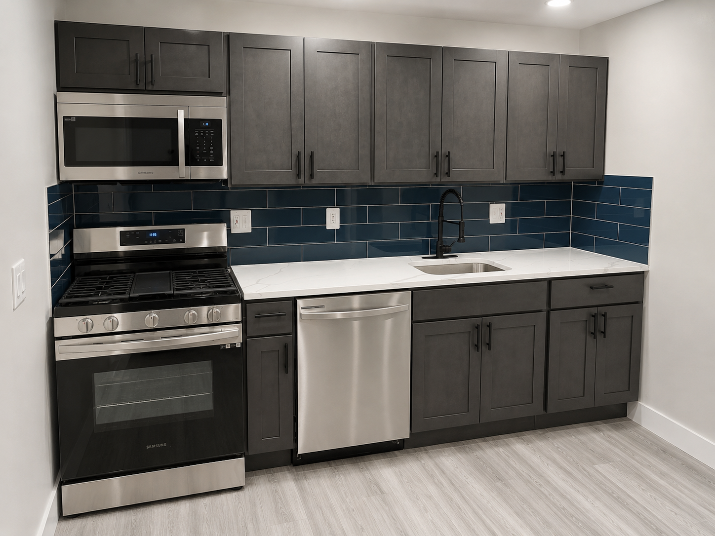 Modern kitchen with gray cabinets, stainless appliances, white counters, and blue tile backsplash