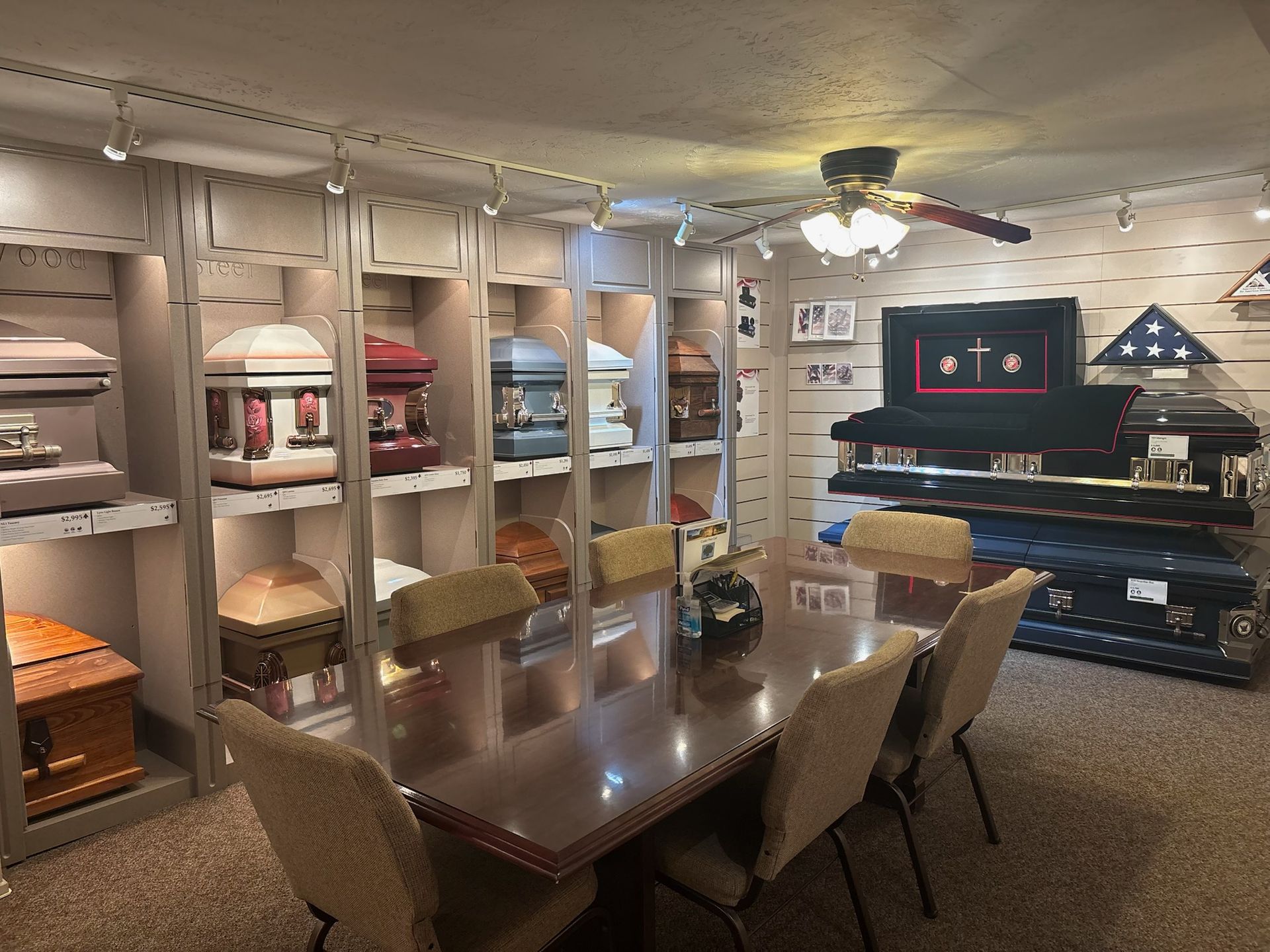 Funeral home showroom displaying coffins, with a table and chairs for consultations.