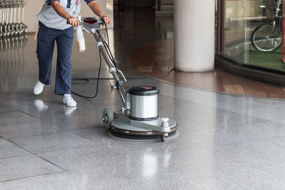 A Man Is Using A Machine To Clean A Tiled Floor — Wyong Commercial Cleaning In Berkeley Vale, NSW