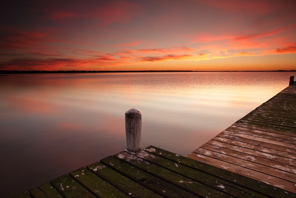 A Wooden Dock Overlooking A Lake At Sunset — Wyong Commercial Cleaning In Berkeley Vale, NSW