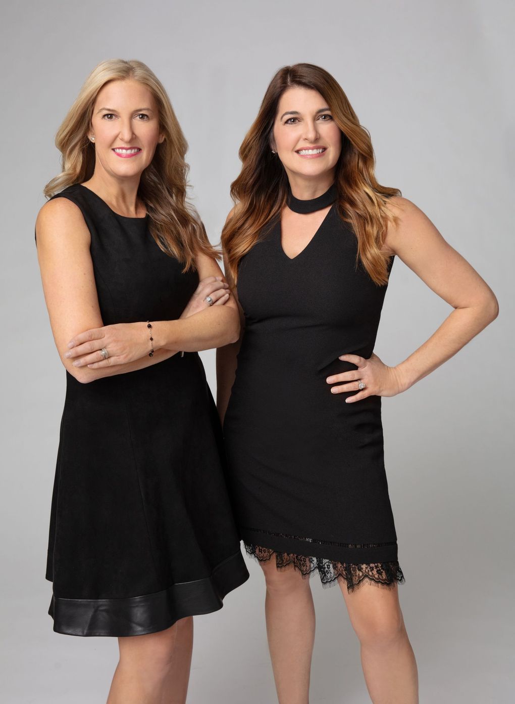 Two women in black dresses are standing next to each other.