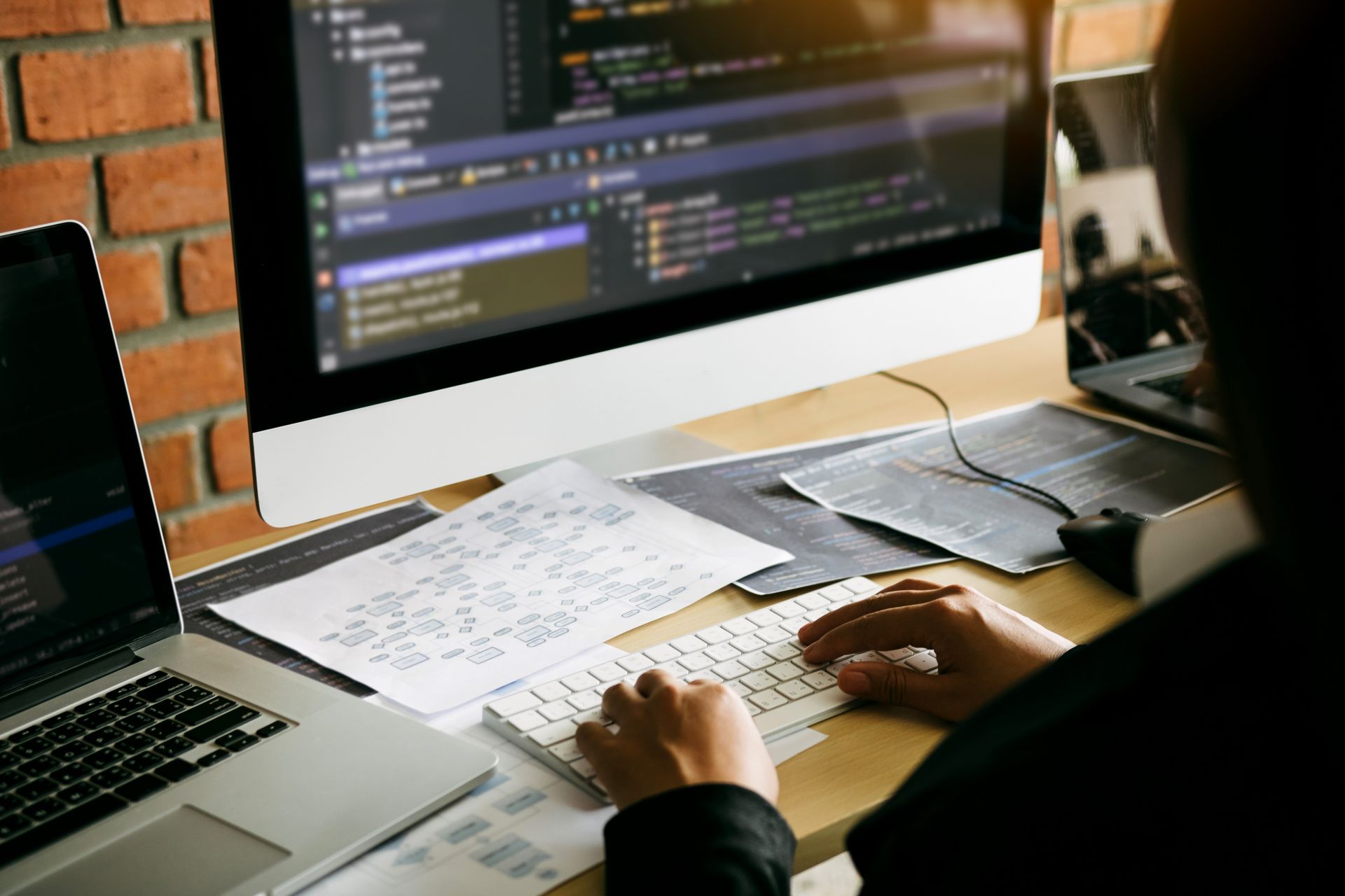 A person is typing on a keyboard in front of a computer.