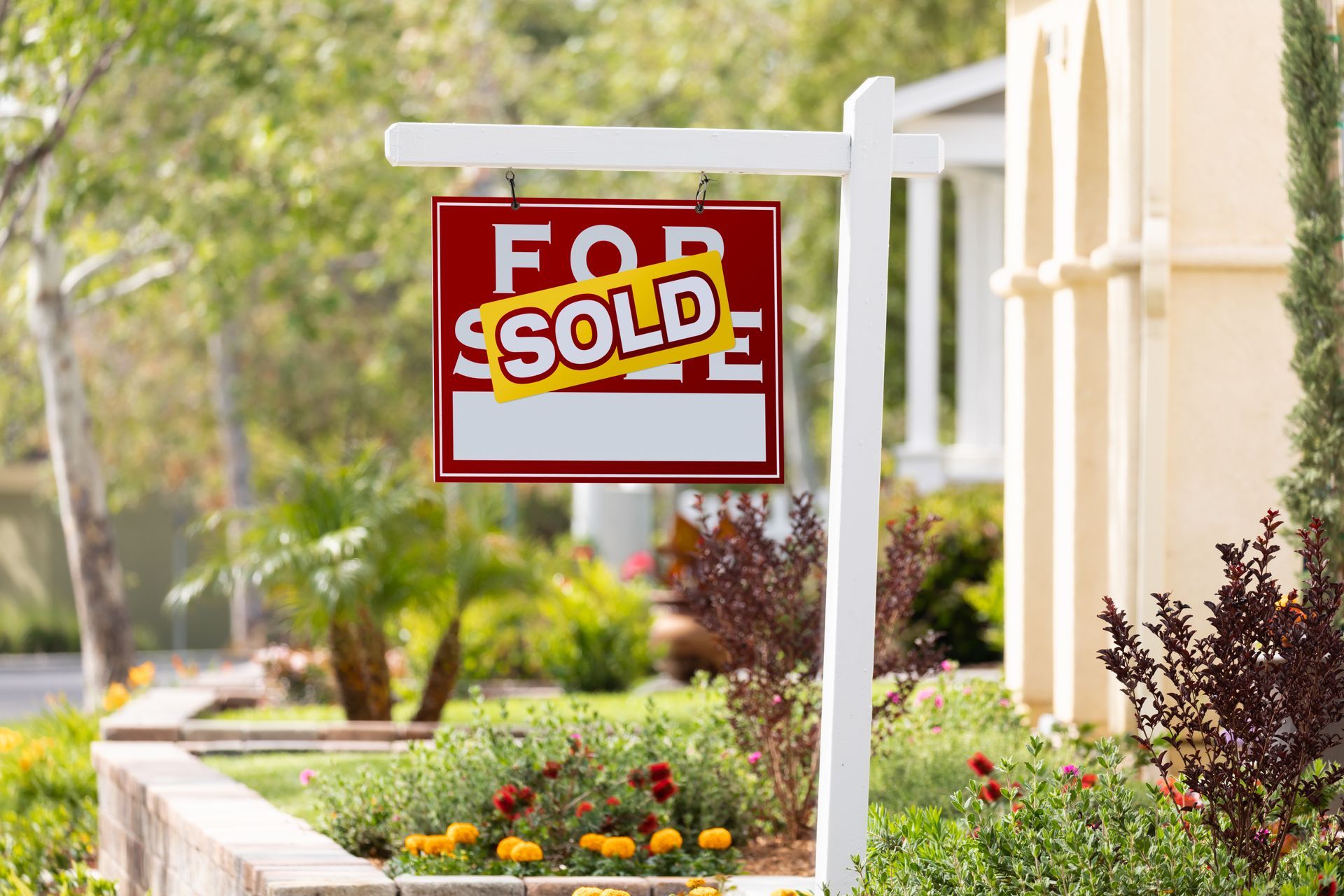 A for sale sign is hanging in front of a house.
