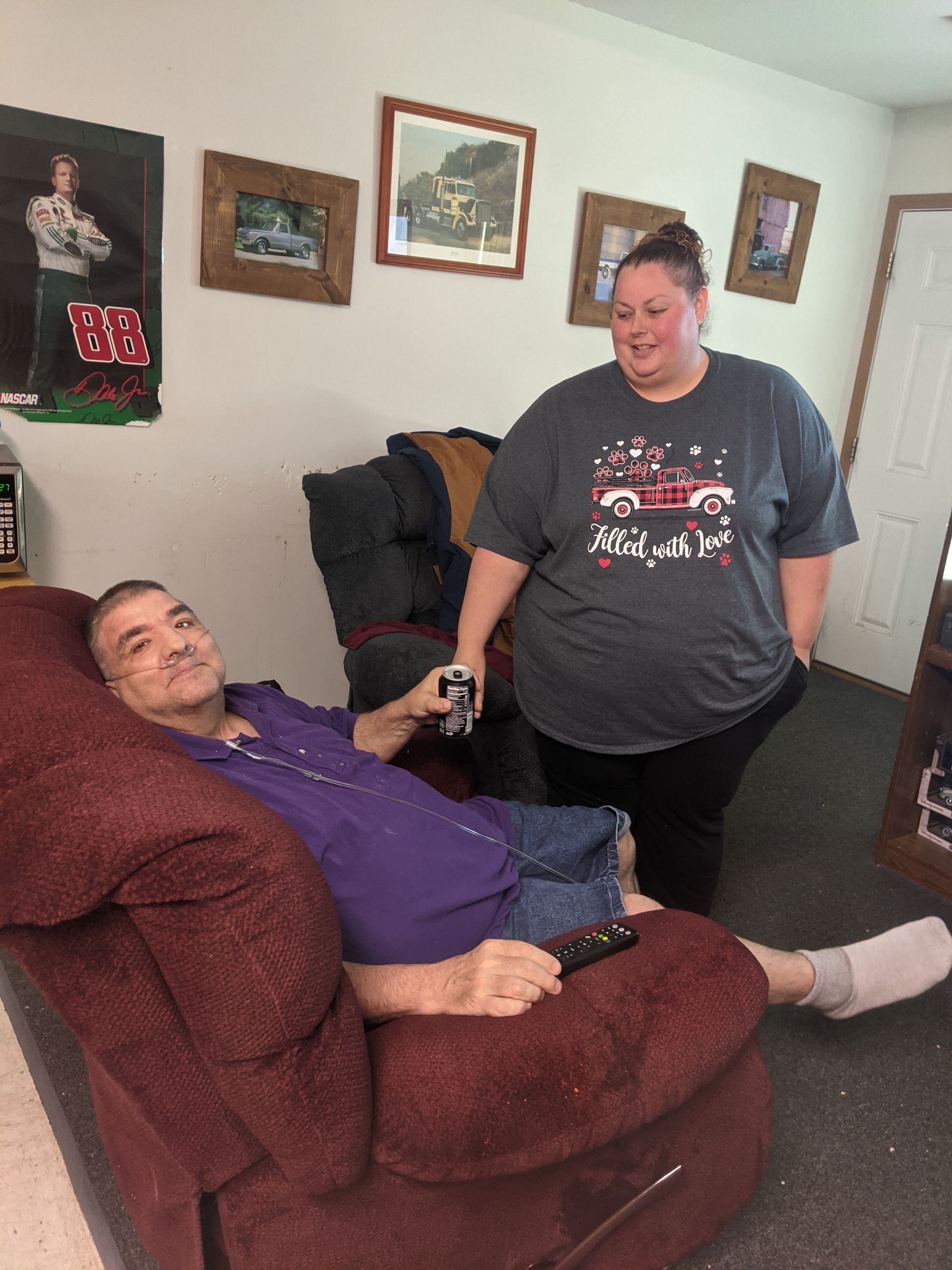 A man is laying on a couch while a woman stands next to him.