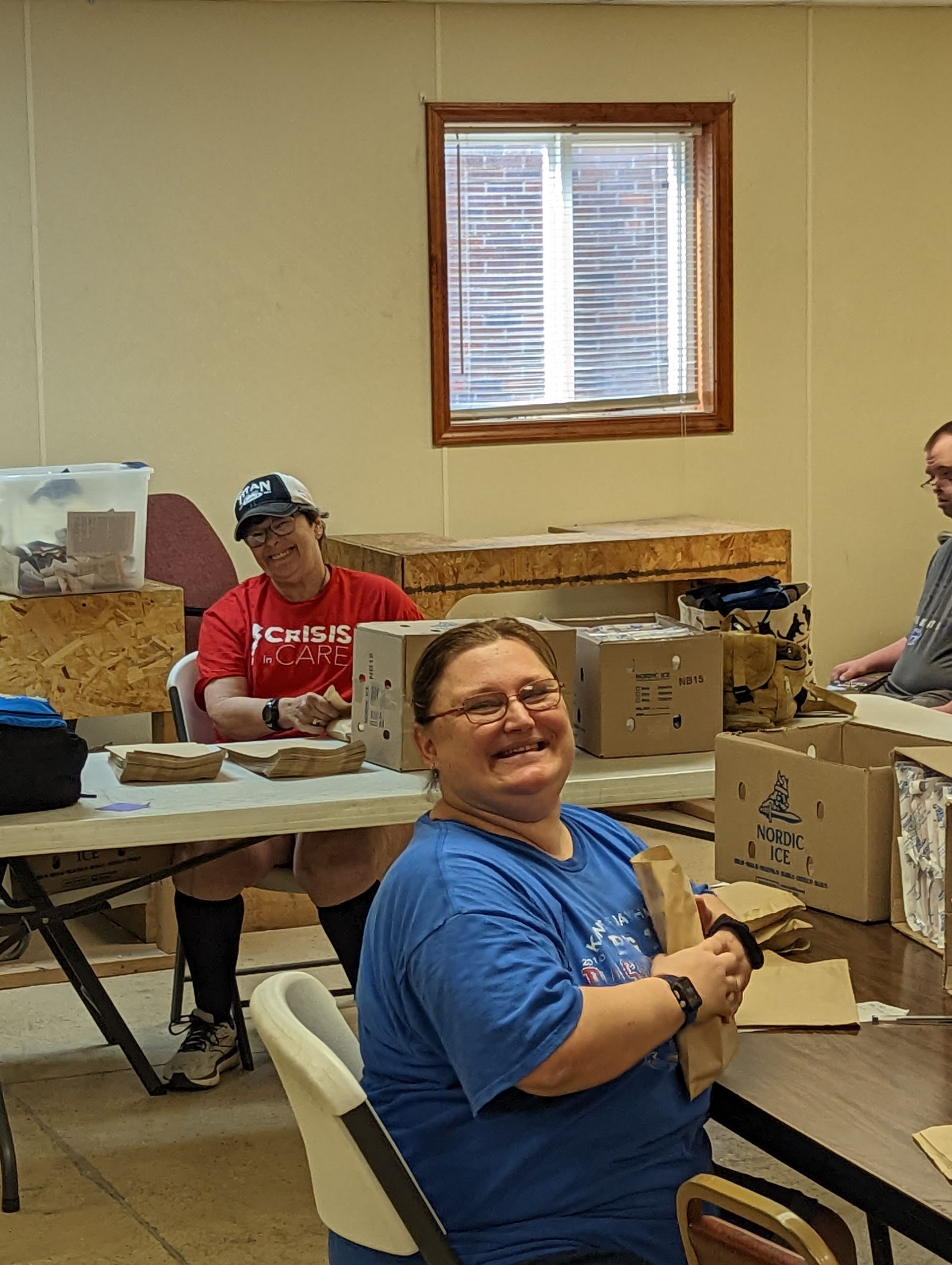 A woman in a blue shirt is smiling while sitting at a table with other people.
