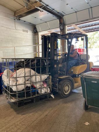 A man is driving a forklift in a garage.