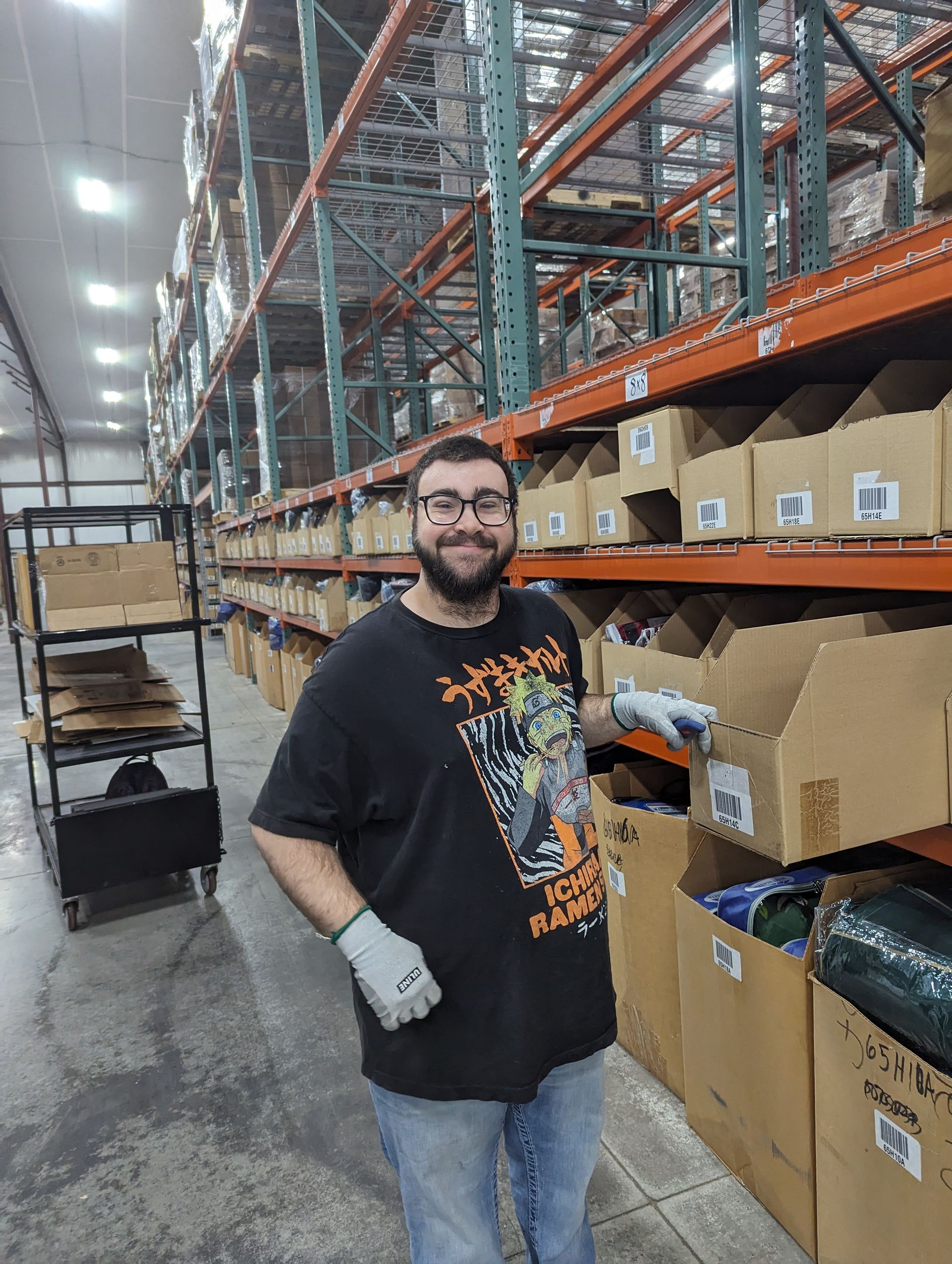A man is standing in a warehouse holding a box.