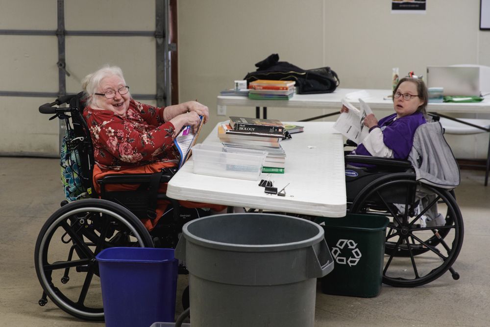 Two women in wheelchairs are sitting at a table.