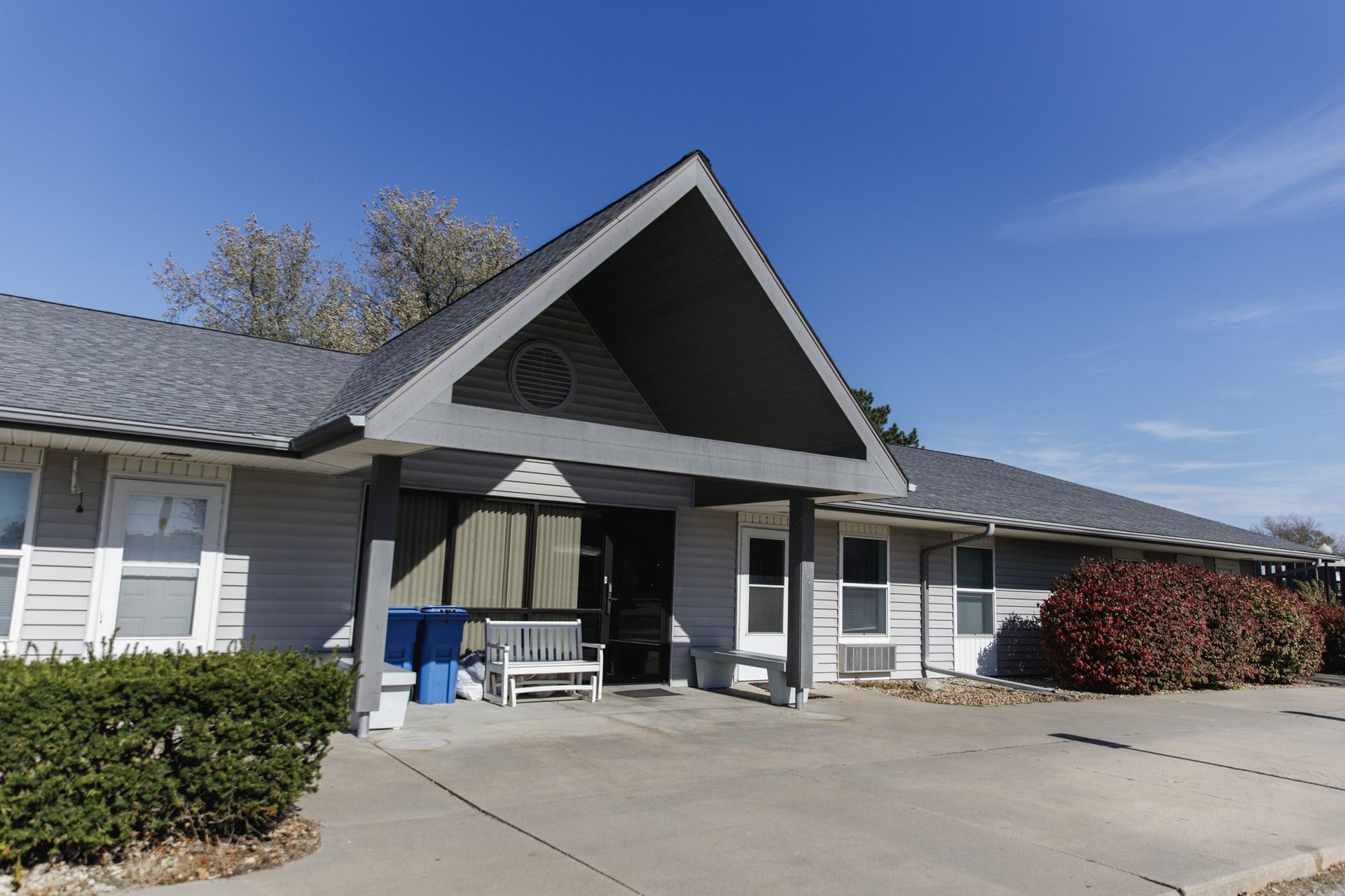 A large house with a gray roof and a bench in front of it