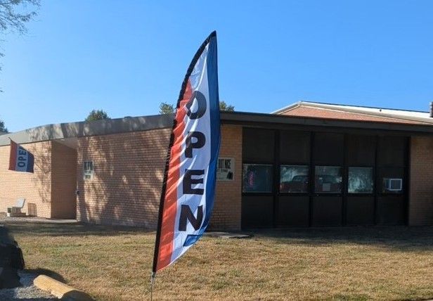 An open flag is flying in front of a building