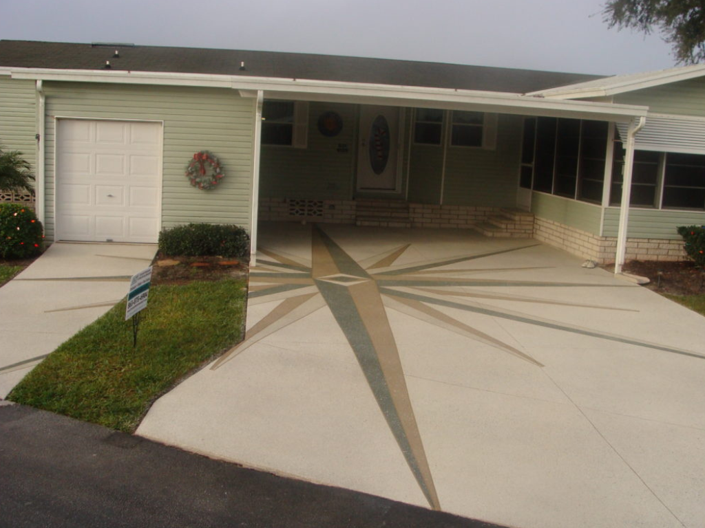 Light green house with a compass rose design on the concrete driveway.