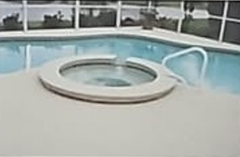 Pool with attached spa. Blue water, light concrete deck, white handrail.