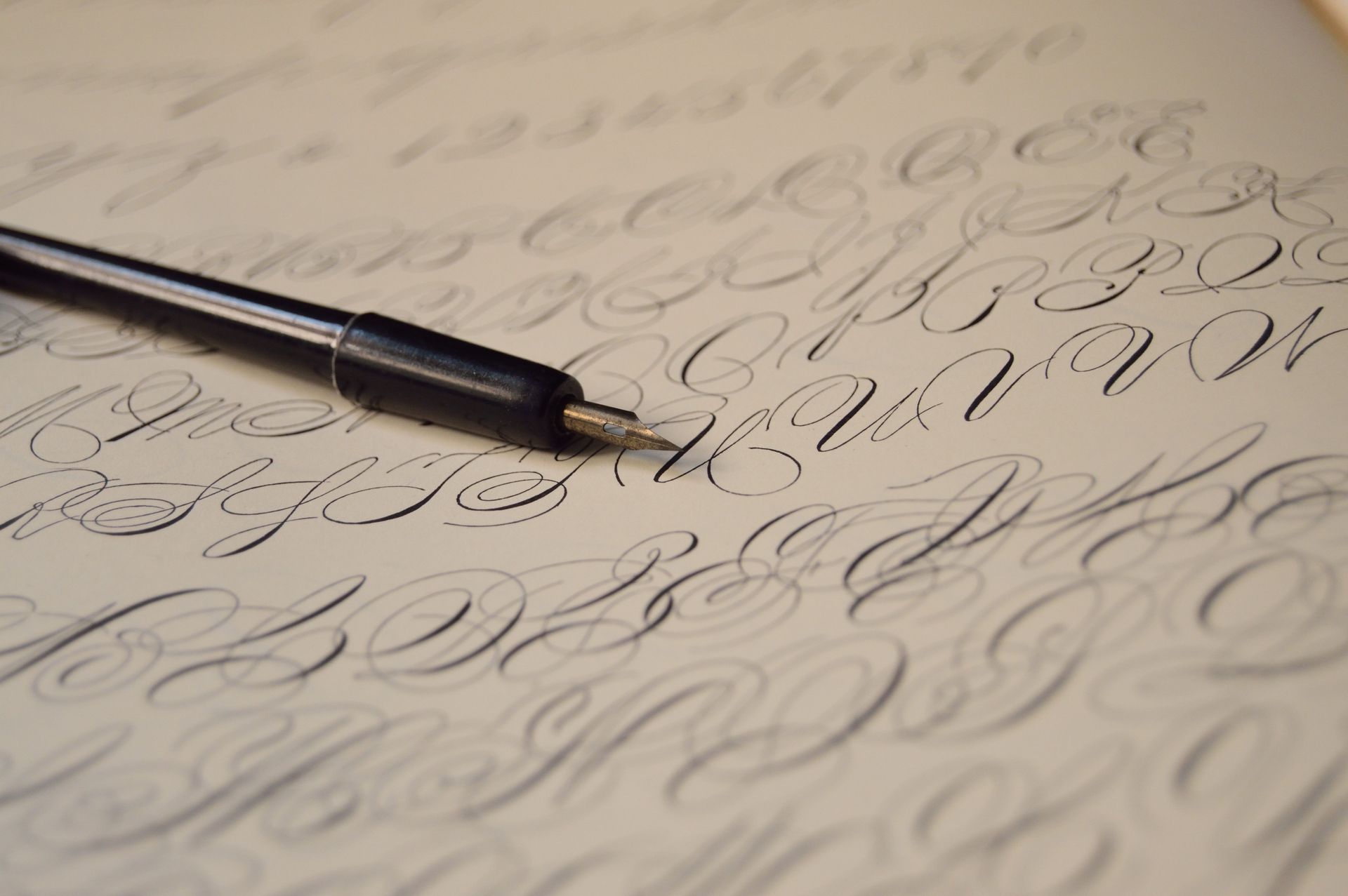 Close-up of a pen on paper with flowing cursive handwriting in the background