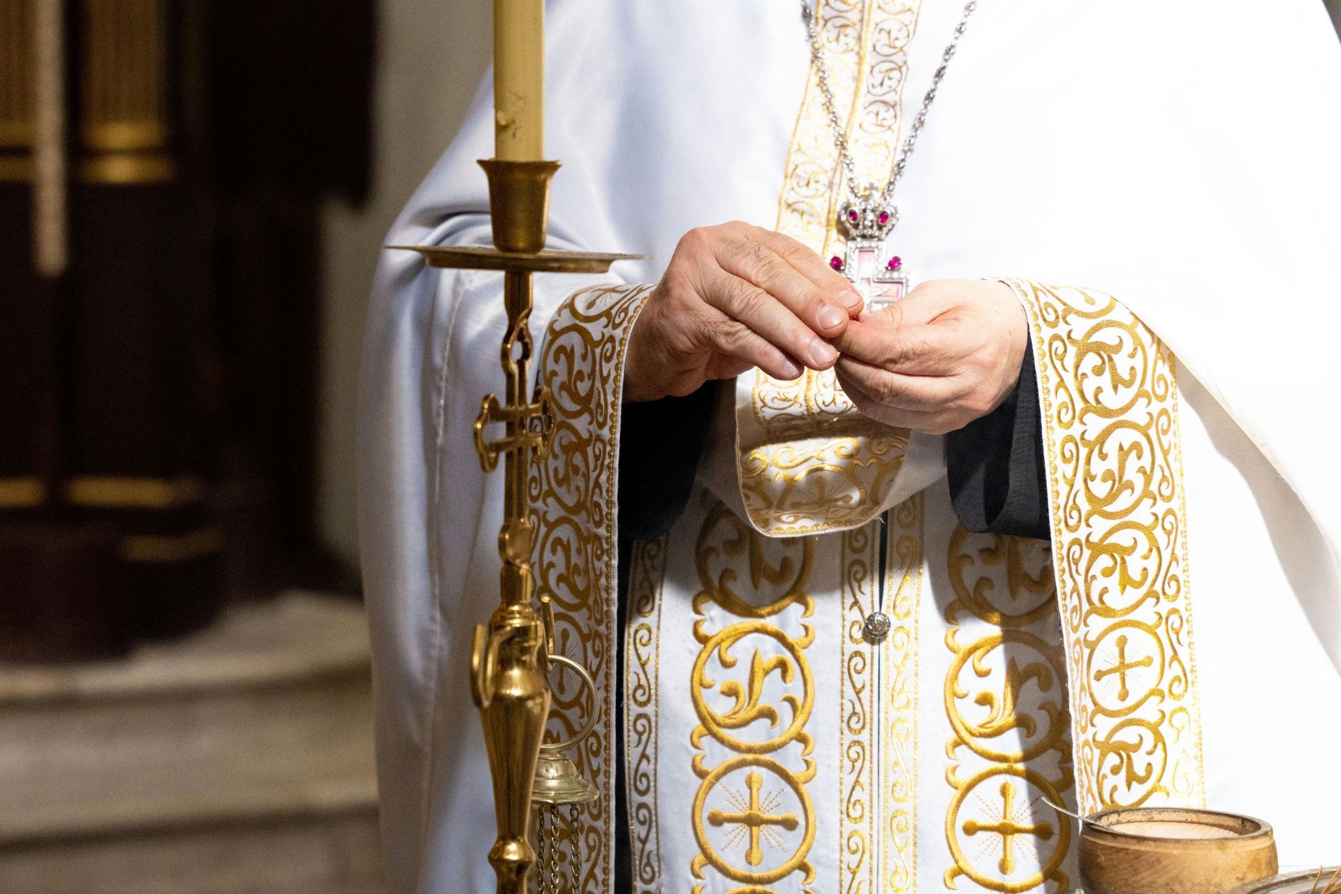 International Funeral Service Southview Trenton NJ - Priest in white and gold vestments holding a chalice during a church.