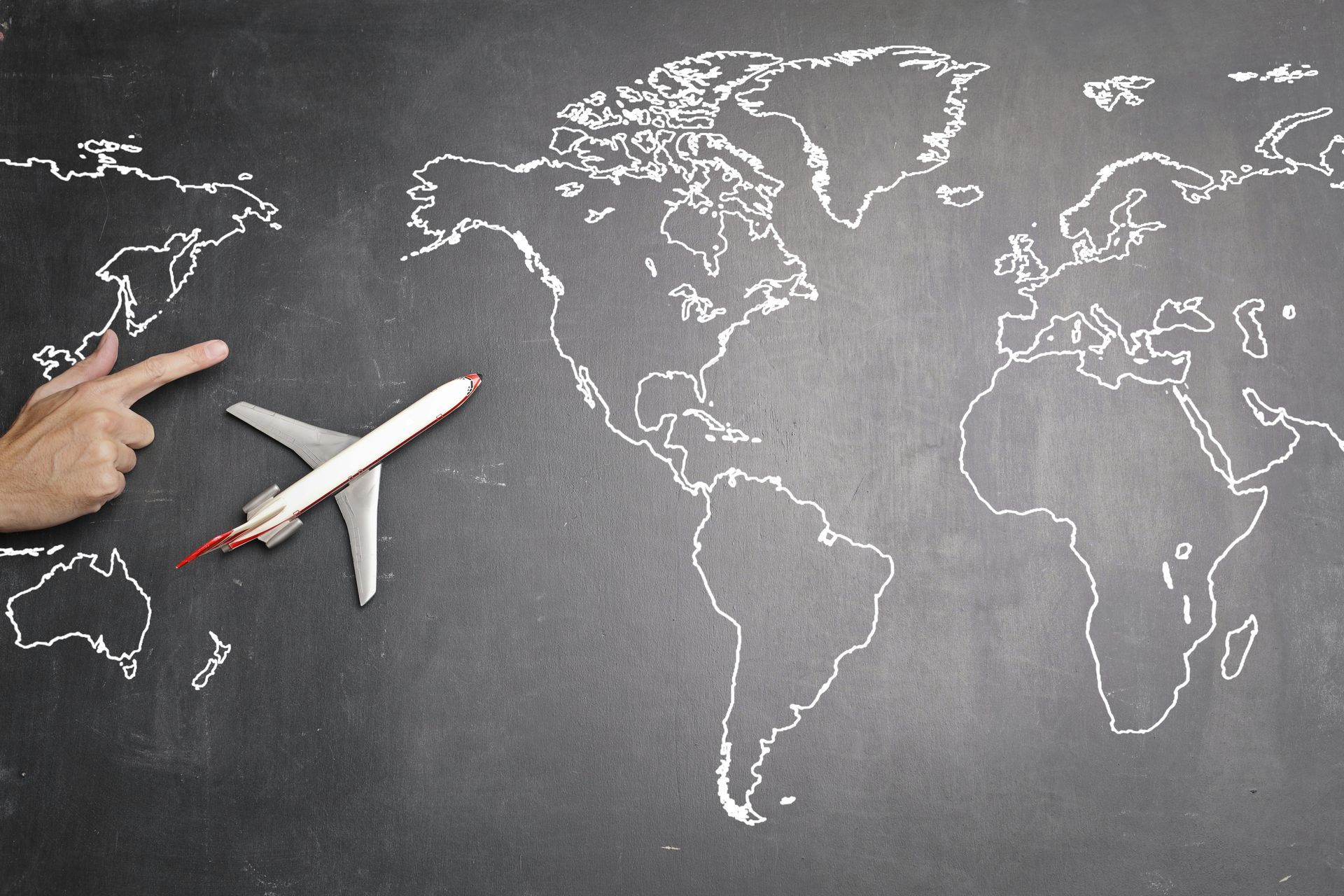 International Funeral Service Southview Trenton NJ - Hand pointing at a world map beside a small airplane on a chalkboard.