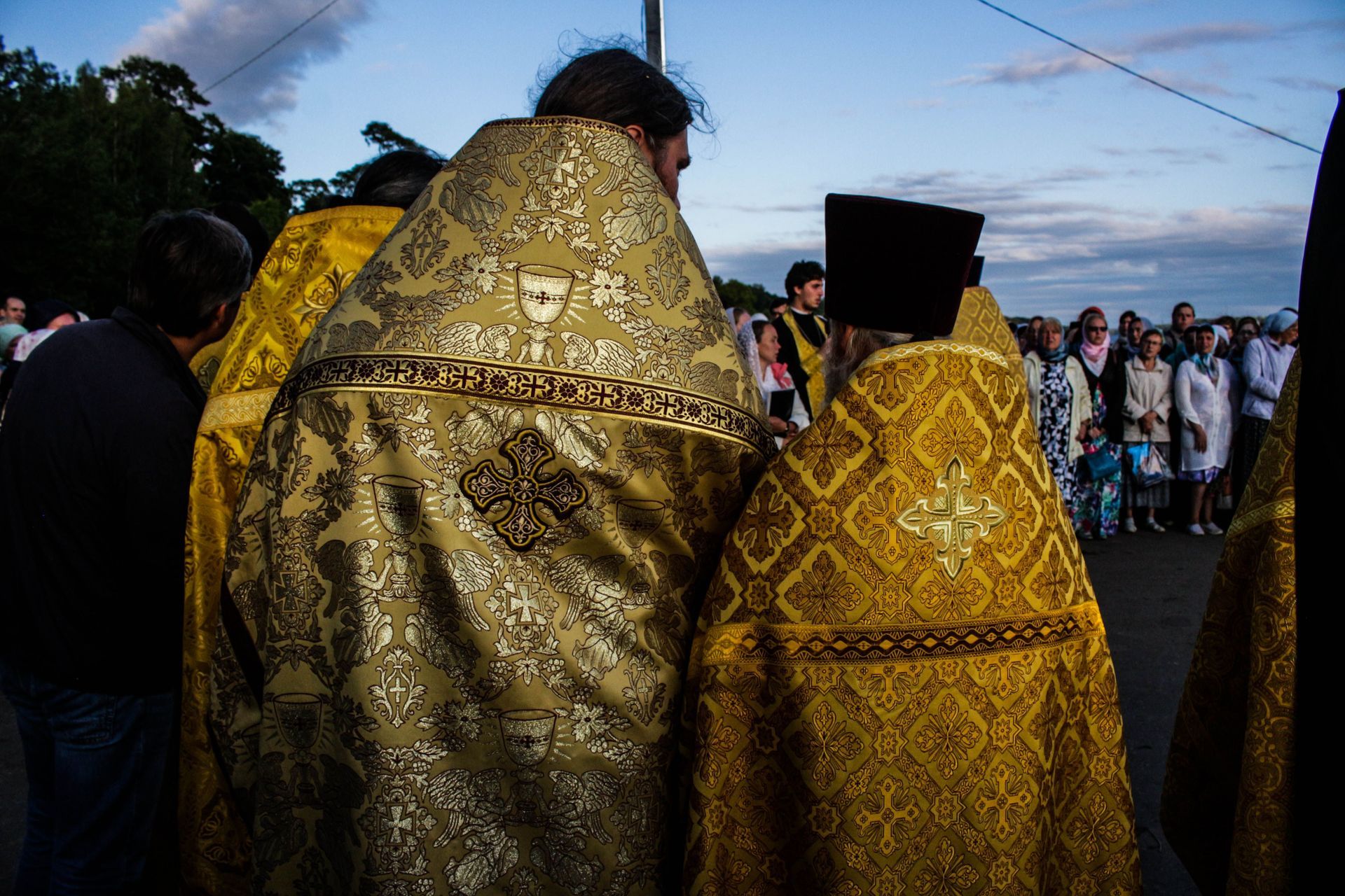 International Funeral Service Southview Trenton NJ - People in gold ceremonial robes stand outdoors at dusk, gathered crowd.