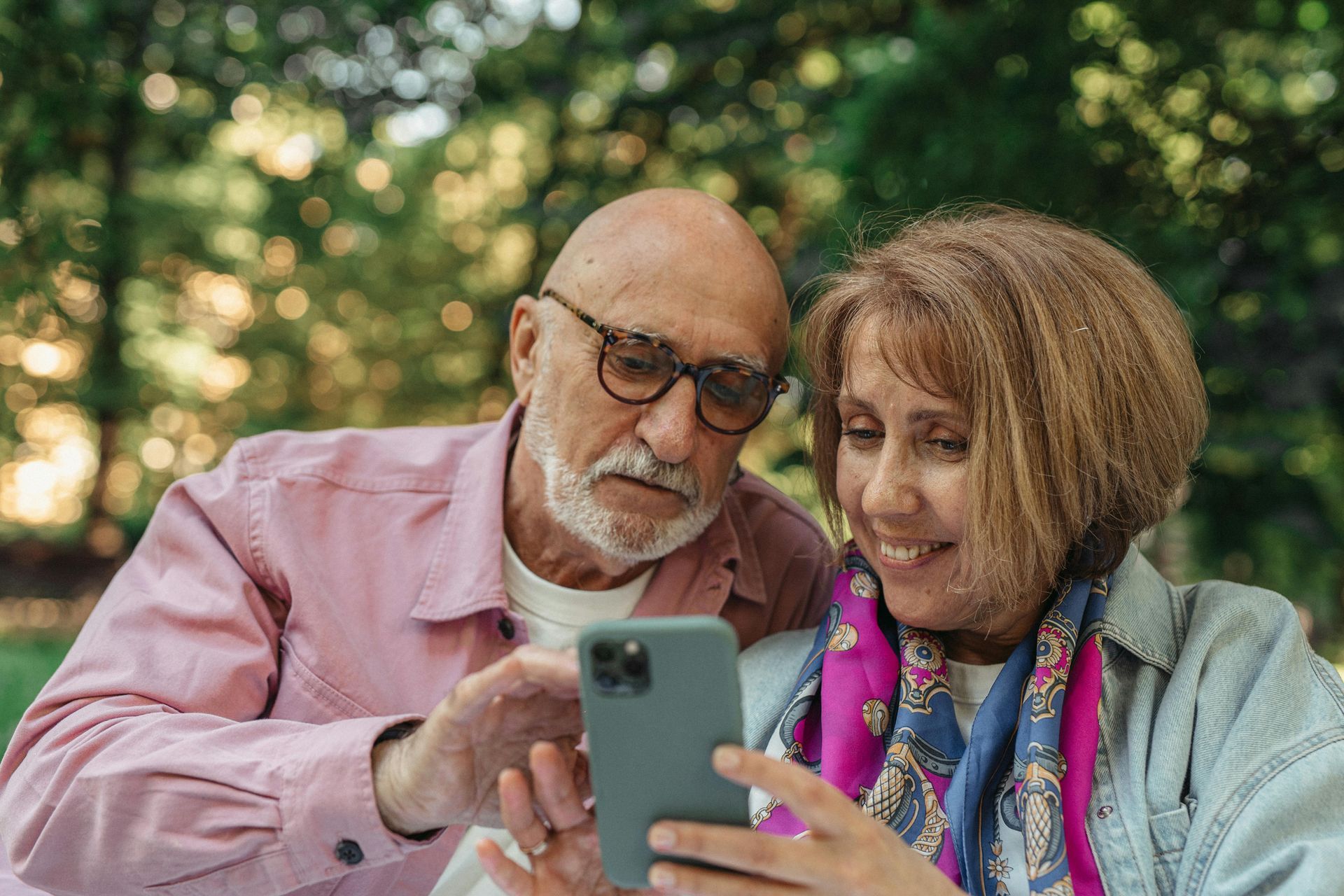 International Funeral Service Southview Trenton NJ - Two people smiling at a smartphone outdoors, with green trees.