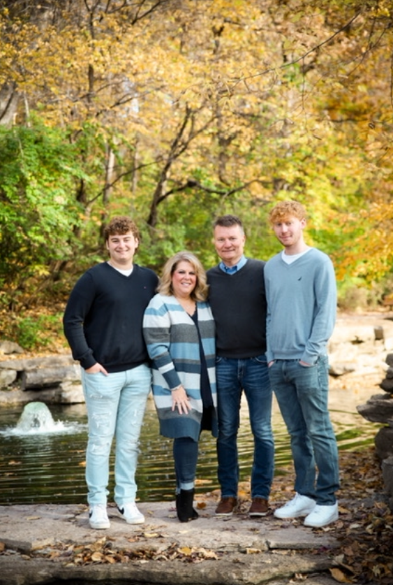 A family is posing for a picture in front of a pond.