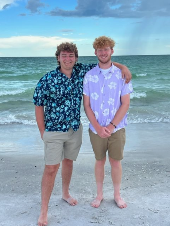 Two men standing on a beach with their arms around each other