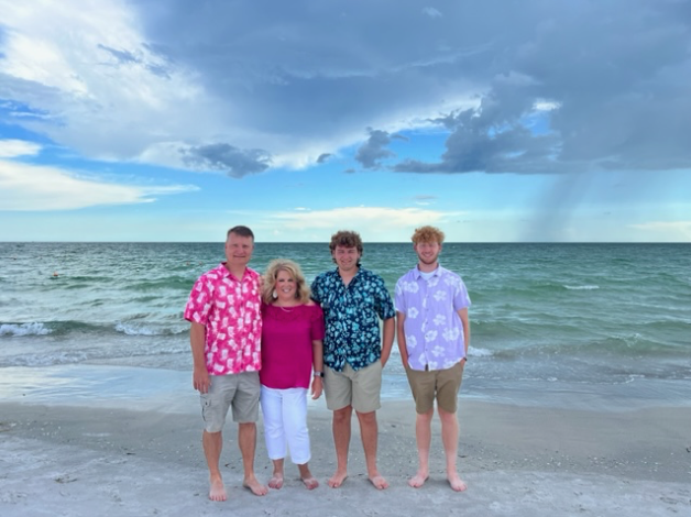 A family is posing for a picture on the beach.