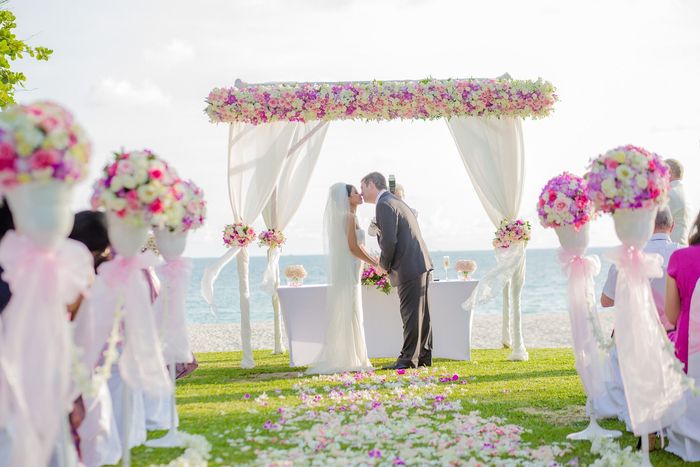 A bride and groom kissing at their wedding ceremony on the beach.