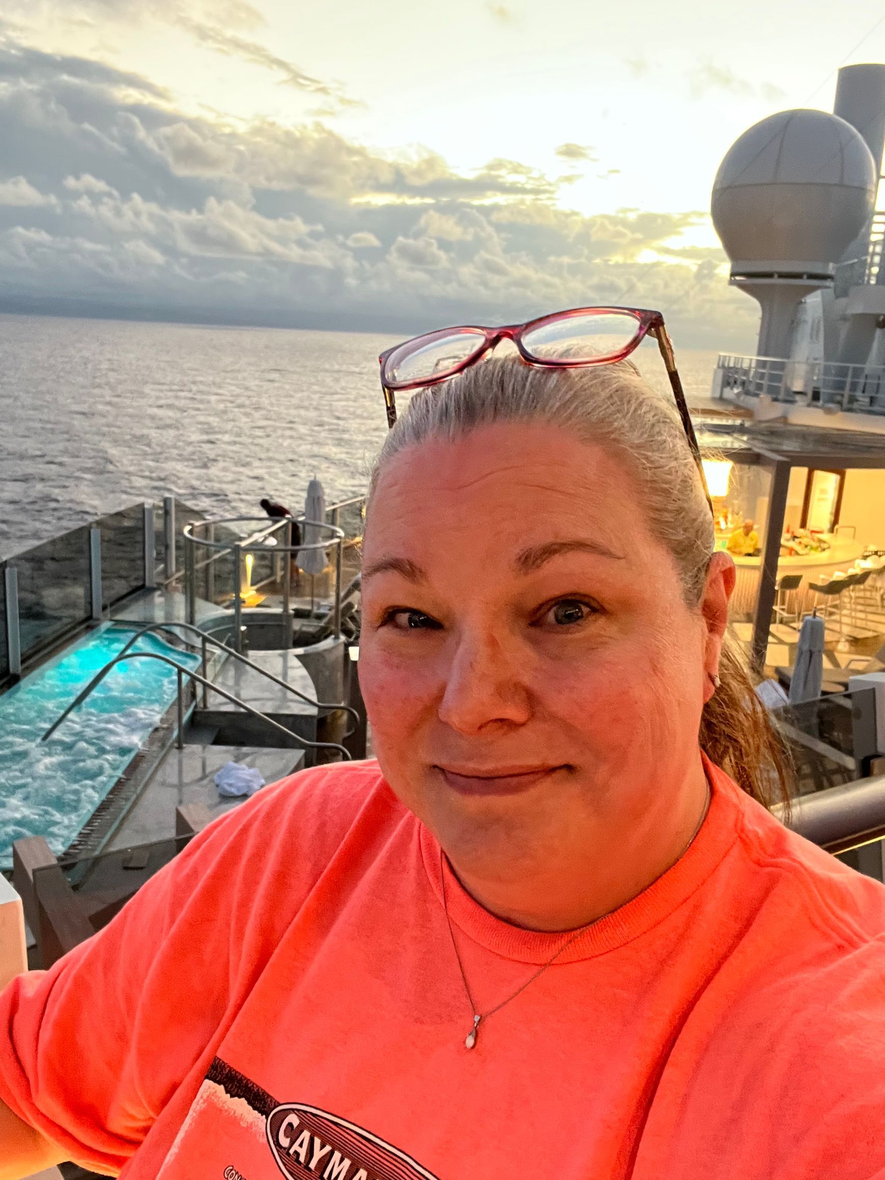 A woman wearing glasses is taking a selfie on a cruise ship.