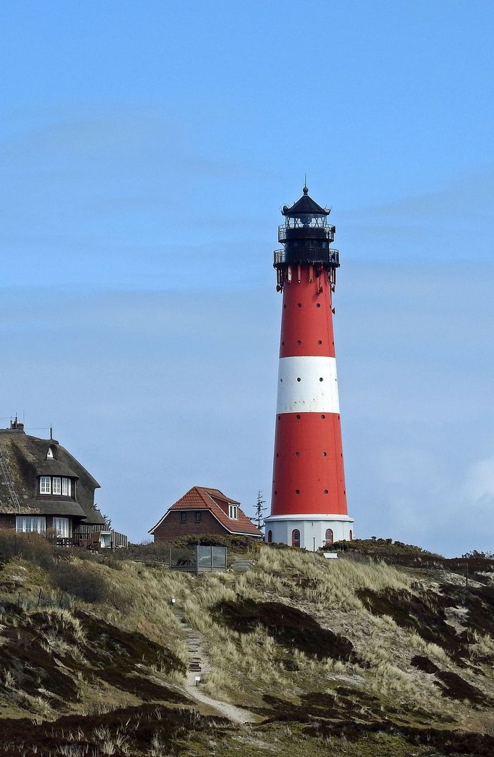 A red and white lighthouse on top of a hill