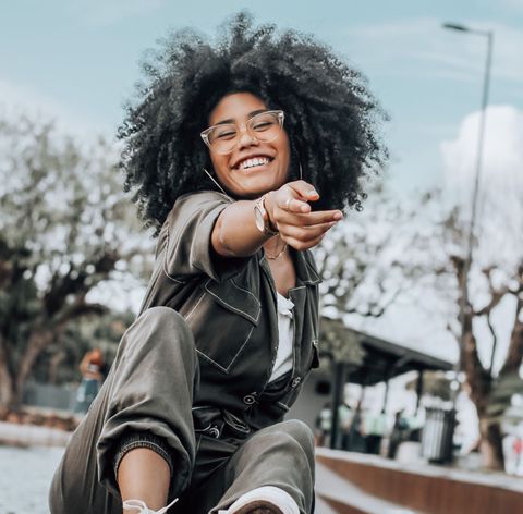 A black woman with glasses, smiles kindly for the camera.