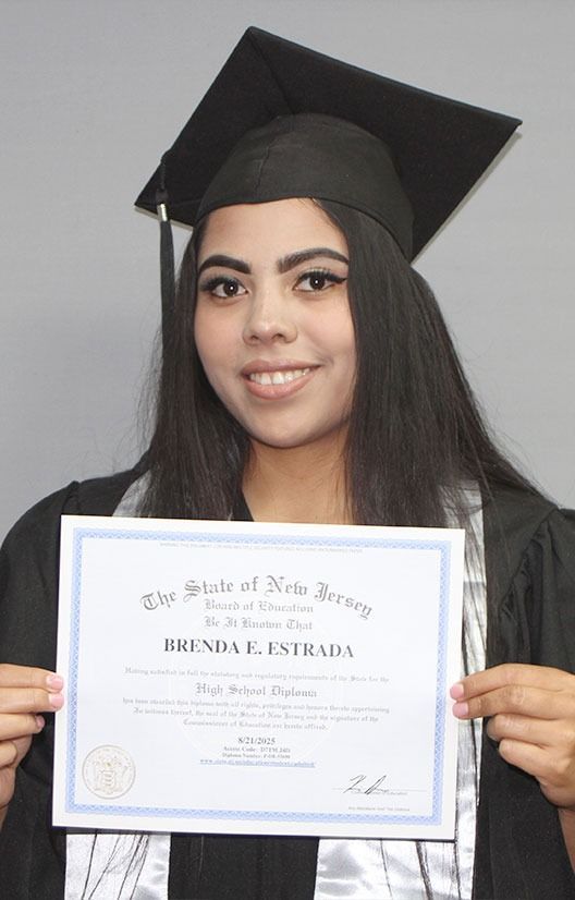 Graduate in black cap and gown holding a diploma, smiling against a gray background