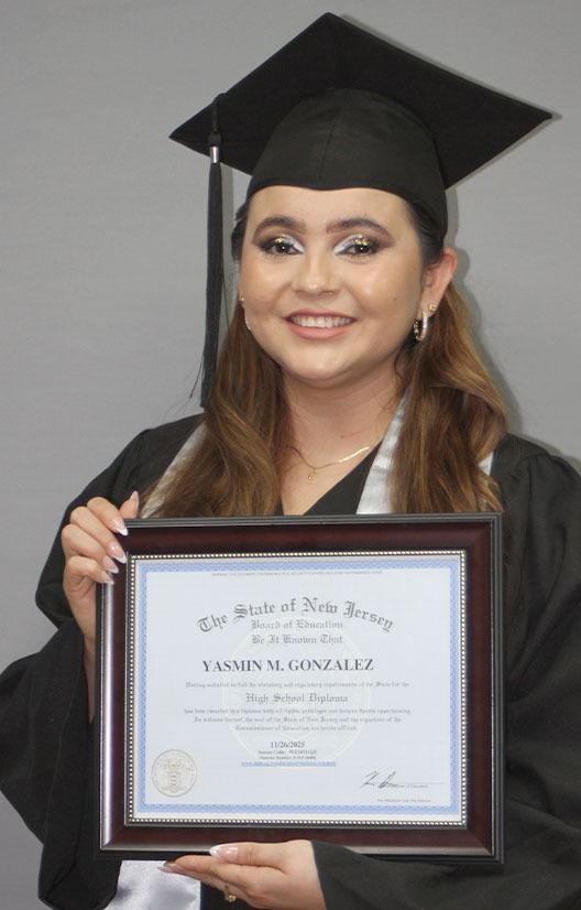 Woman in graduation cap and gown holding a framed diploma and smiling at the camera.