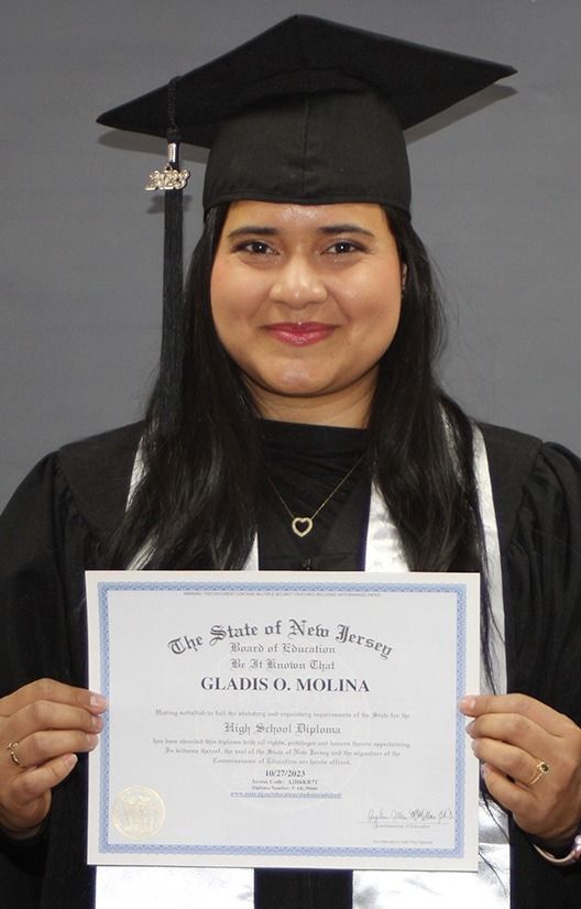 Graduate in black cap and gown holding a diploma against a gray background