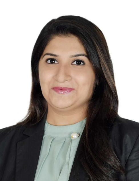 Portrait of a smiling woman in a black blazer and light green blouse on a white background