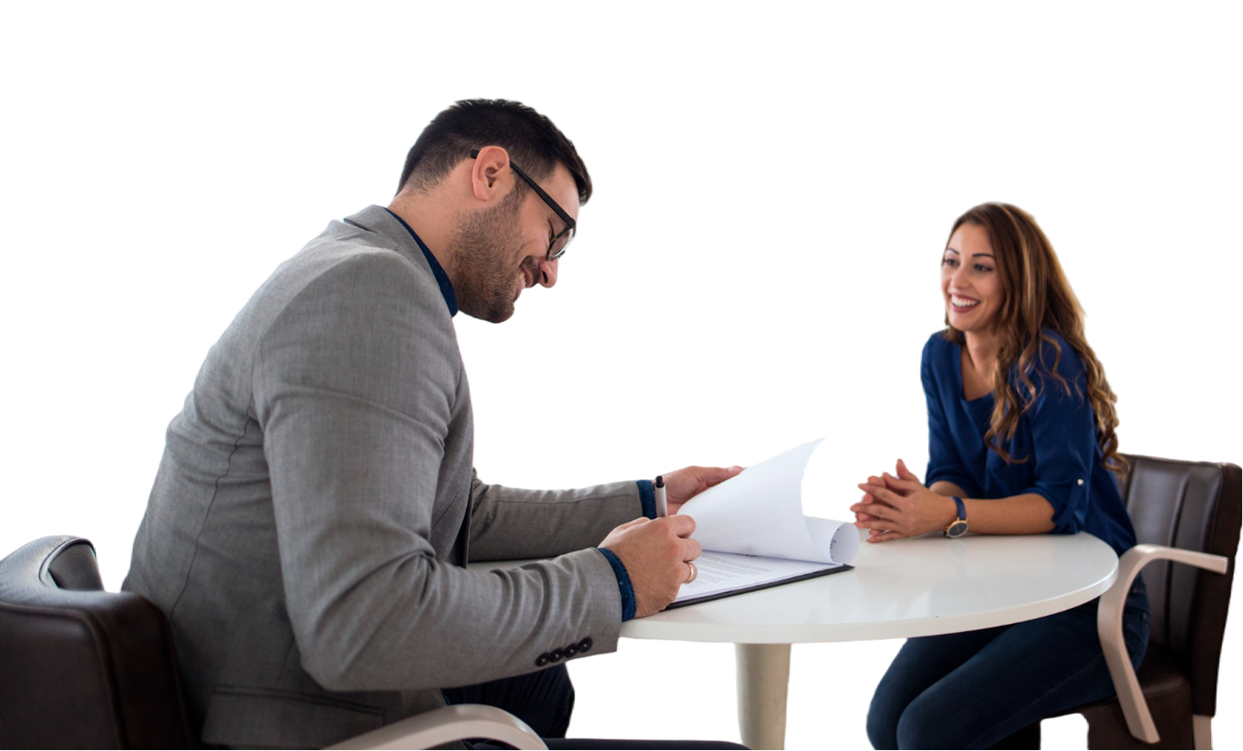 Two people in a meeting across a white table, discussing documents in a bright office.