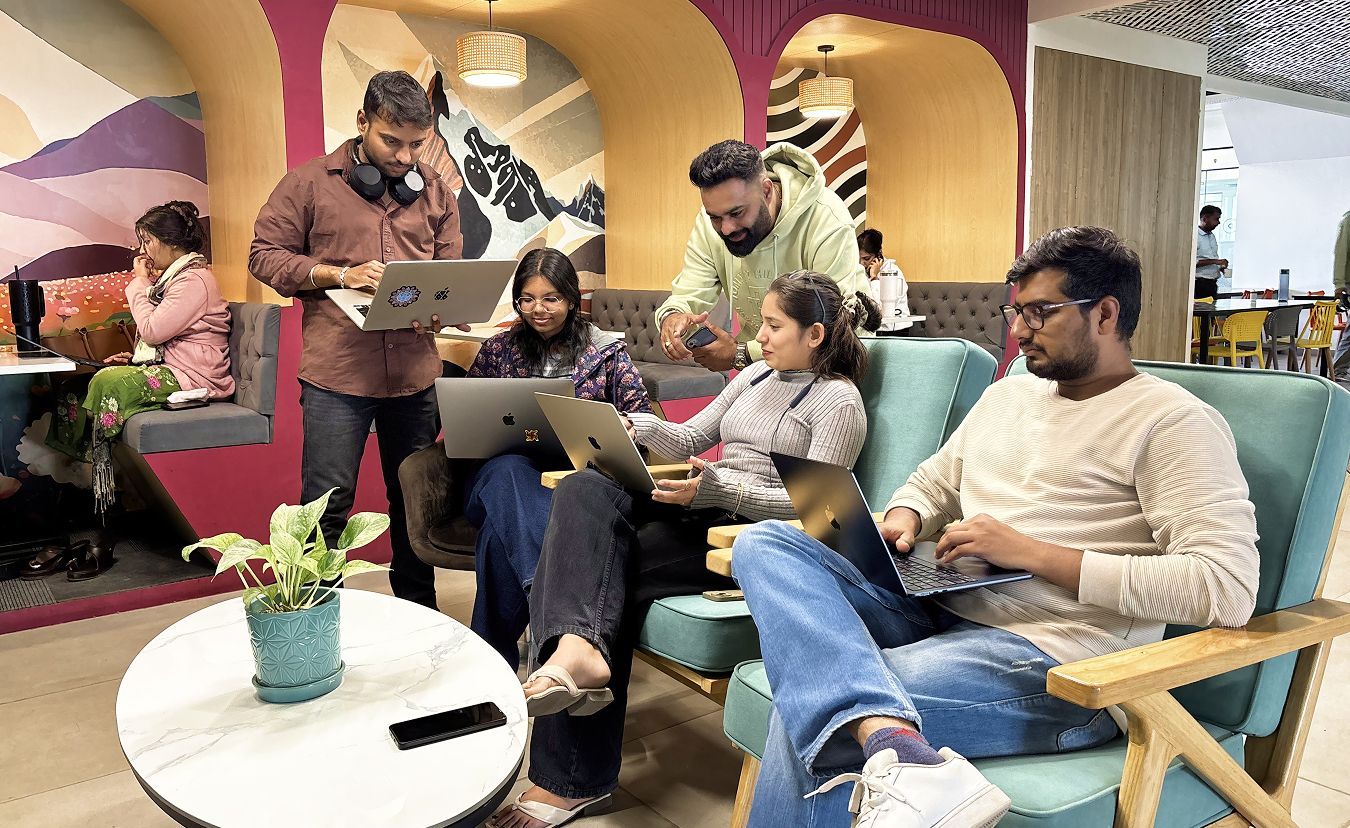 People collaborating on laptops and phones in a cozy lounge with colorful arches and sofas