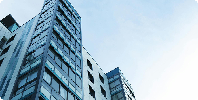 Modern glass apartment buildings viewed from below against a pale sky