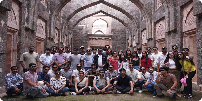 Large group posing in a historic stone hall with arched ceiling and brick walls