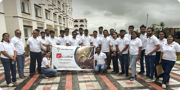Large group in white shirts posing outdoors with a banner in front of a building