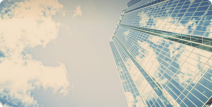 Reflection of a glass skyscraper against a bright cloudy sky