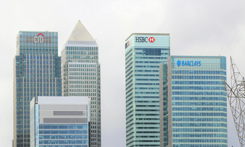 Modern glass office towers with HSBC and Barclays logos against a pale sky