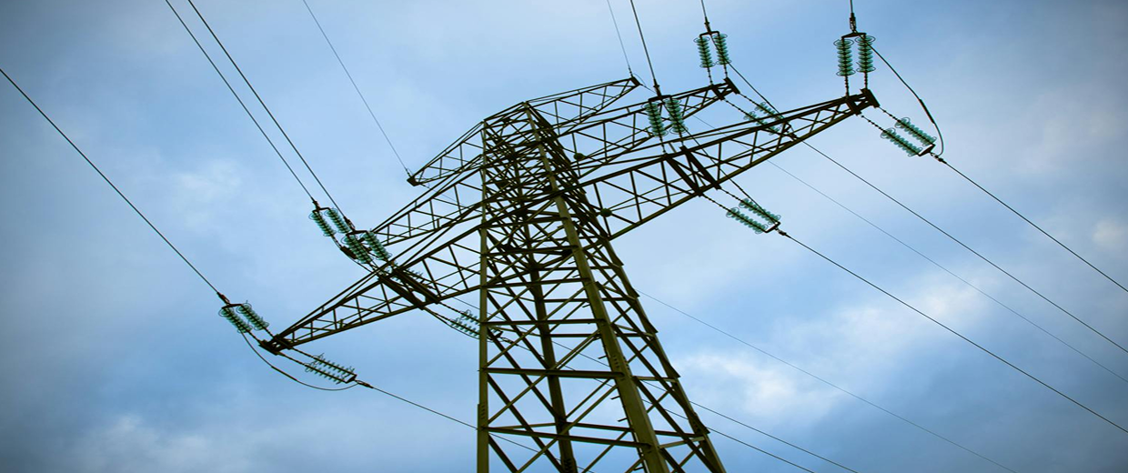 Electric power transmission tower with overhead lines against a blue sky